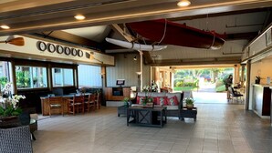 A spacious indoor area with a reception desk, seating arrangements, and a view of the outdoors. - 1 Bedroom Garden View Condo  3rd Floor H304- Pono Kai (Kapaʻa)