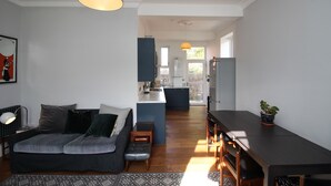 A modern living room with a sofa, a coffee table, and a dining area with a table and chairs. - Troon Golf 2024 (Troon)
