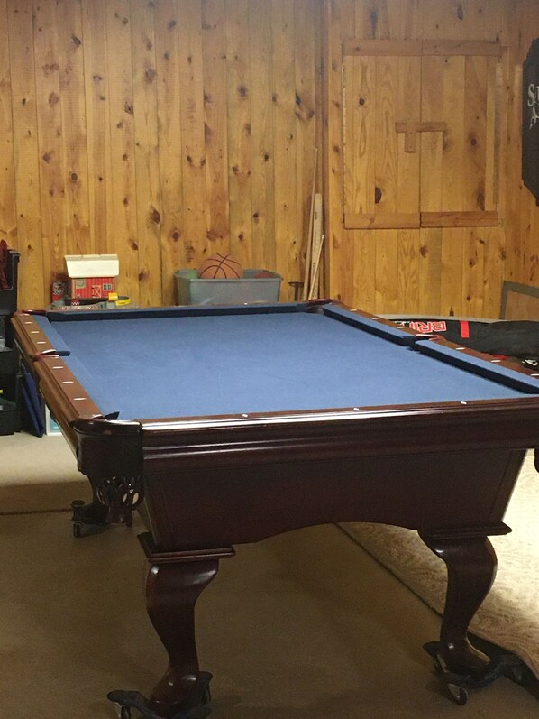 A pool table in a room with wooden walls and a door.