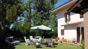 A patio with a table and chairs, surrounded by potted plants and a white building with a tiled roof. - B&B Fra e Fe (Arborea)