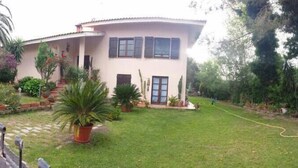 A two-story house with a curved roof, a front porch, and a well-maintained lawn. - B&B Fra e Fe (Arborea)
