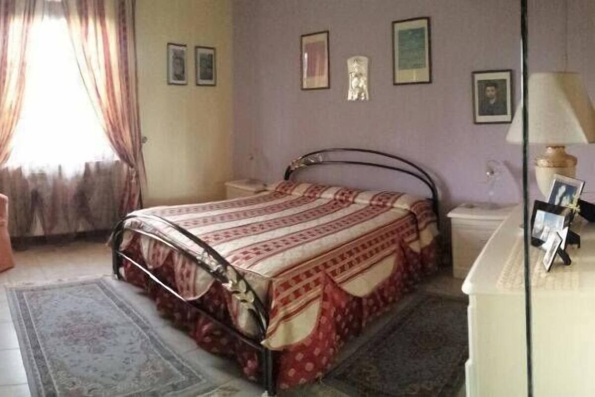 A bedroom with a bed, a chair, a dresser, and a mirror.