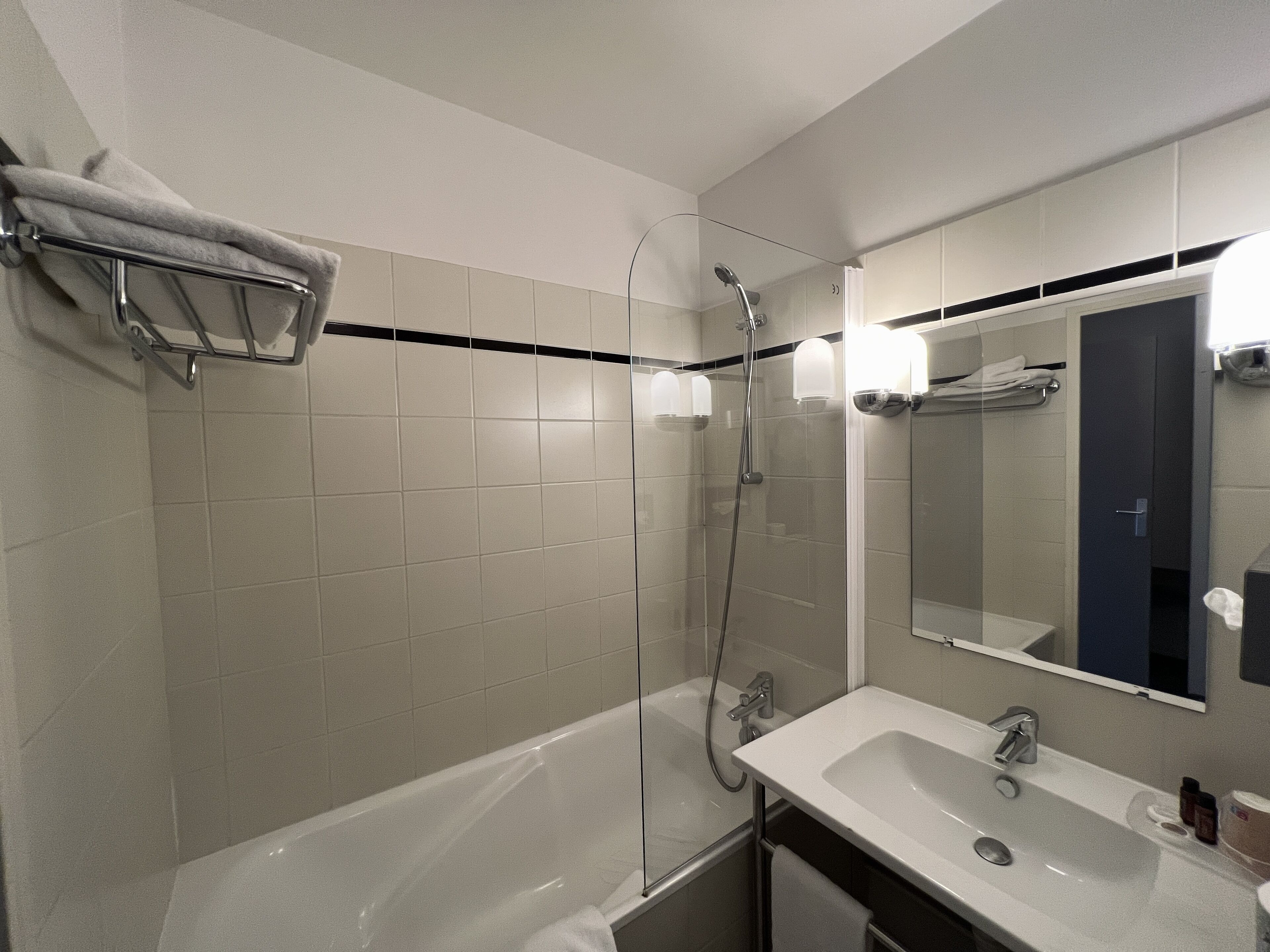 Une salle de bain moderne avec une douche à parois de verre, une baignoire blanche et un lavabo surmonté d’un miroir.