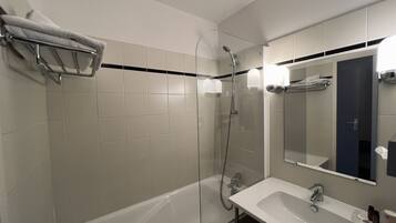 Une salle de bain moderne avec une douche à parois de verre, une baignoire blanche et un lavabo surmonté d’un miroir.