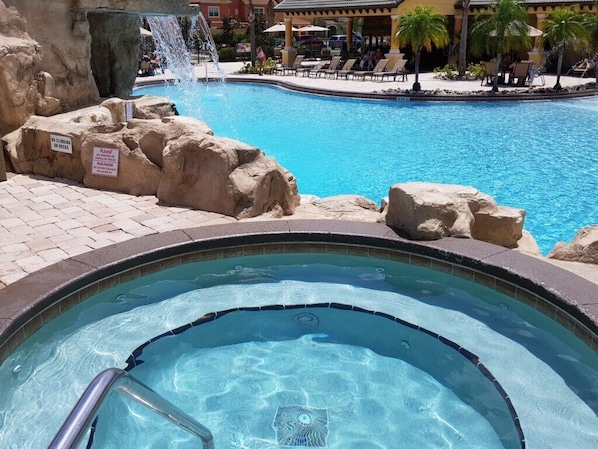 A swimming pool with a hot tub, a waterfall feature, and lounge chairs. - 8926mp - Paradise Palms (Kissimmee)