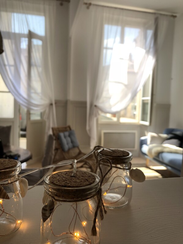 A cozy room with a table displaying jars with cork stoppers and fairy lights.