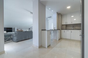 Eine moderne Wohnung mit Wohnbereich, Küchenzeile und Essbereich.