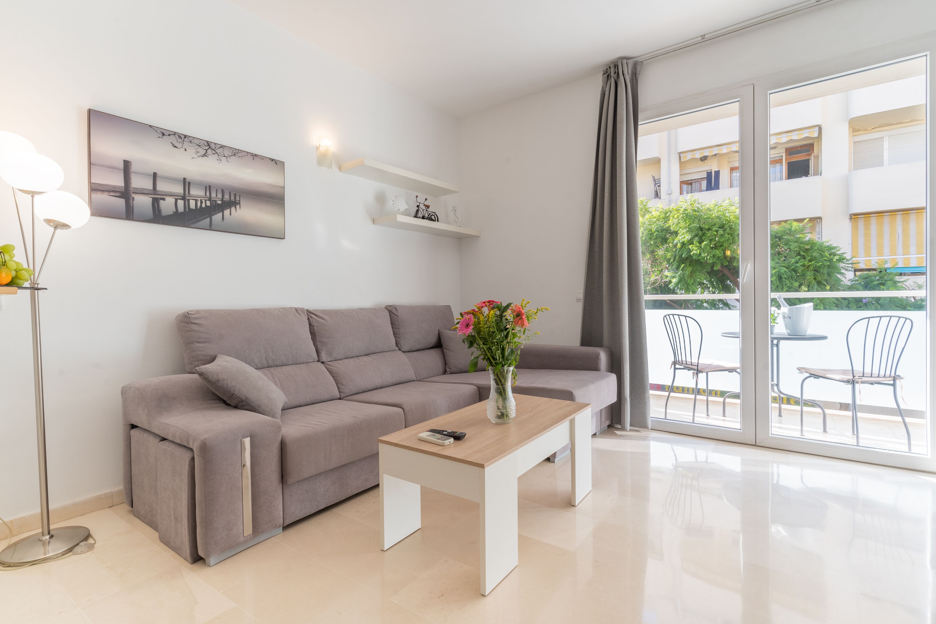 A modern living room with a grey sofa, a wooden coffee table, and a painting on the wall.