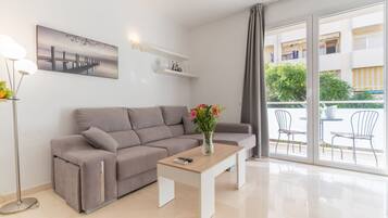 A modern living room with a grey sofa, a wooden coffee table, and a painting on the wall.