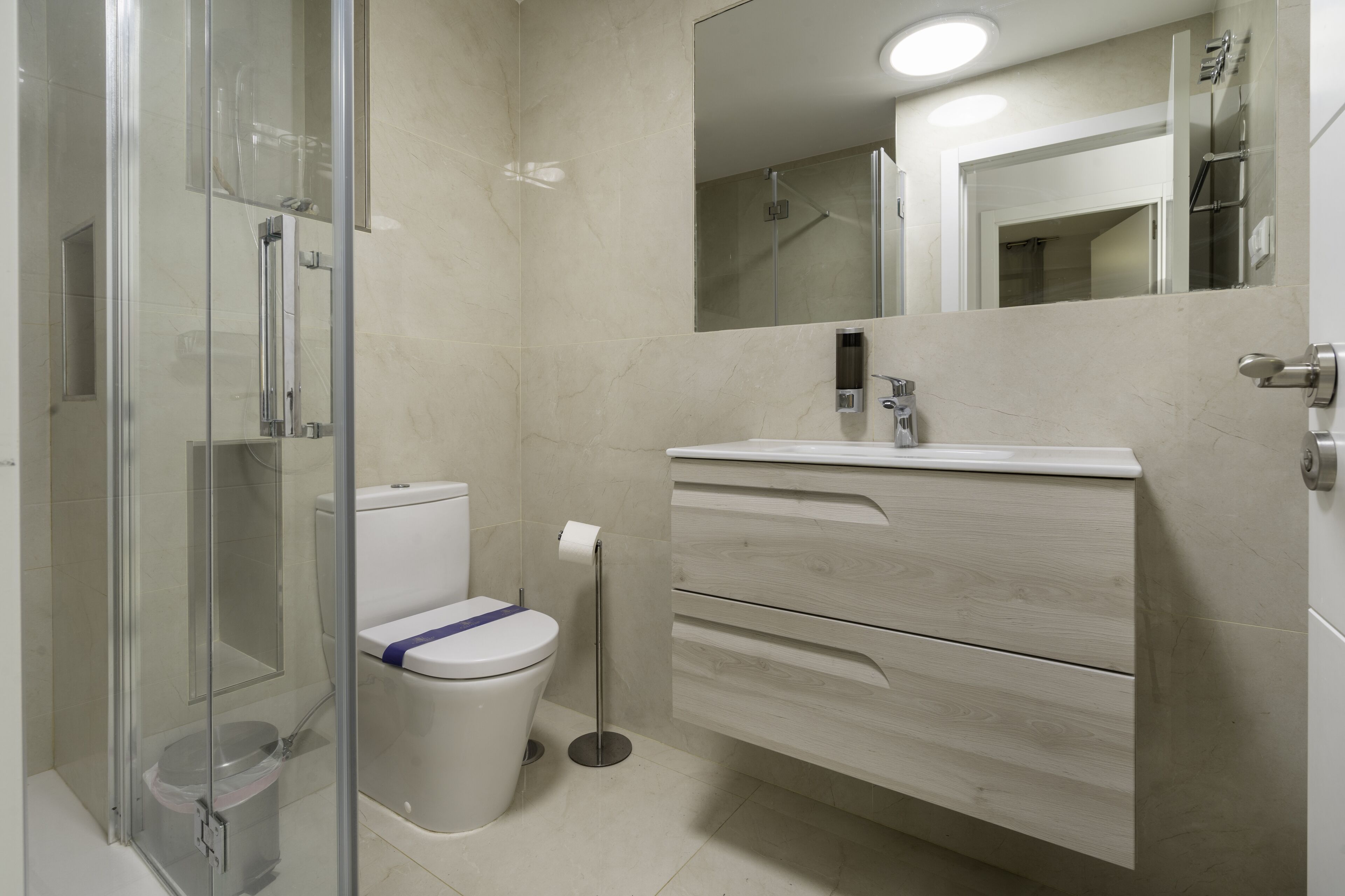 Une salle de bain moderne avec une douche à parois de verre, des toilettes et un meuble-lavabo avec des tiroirs.