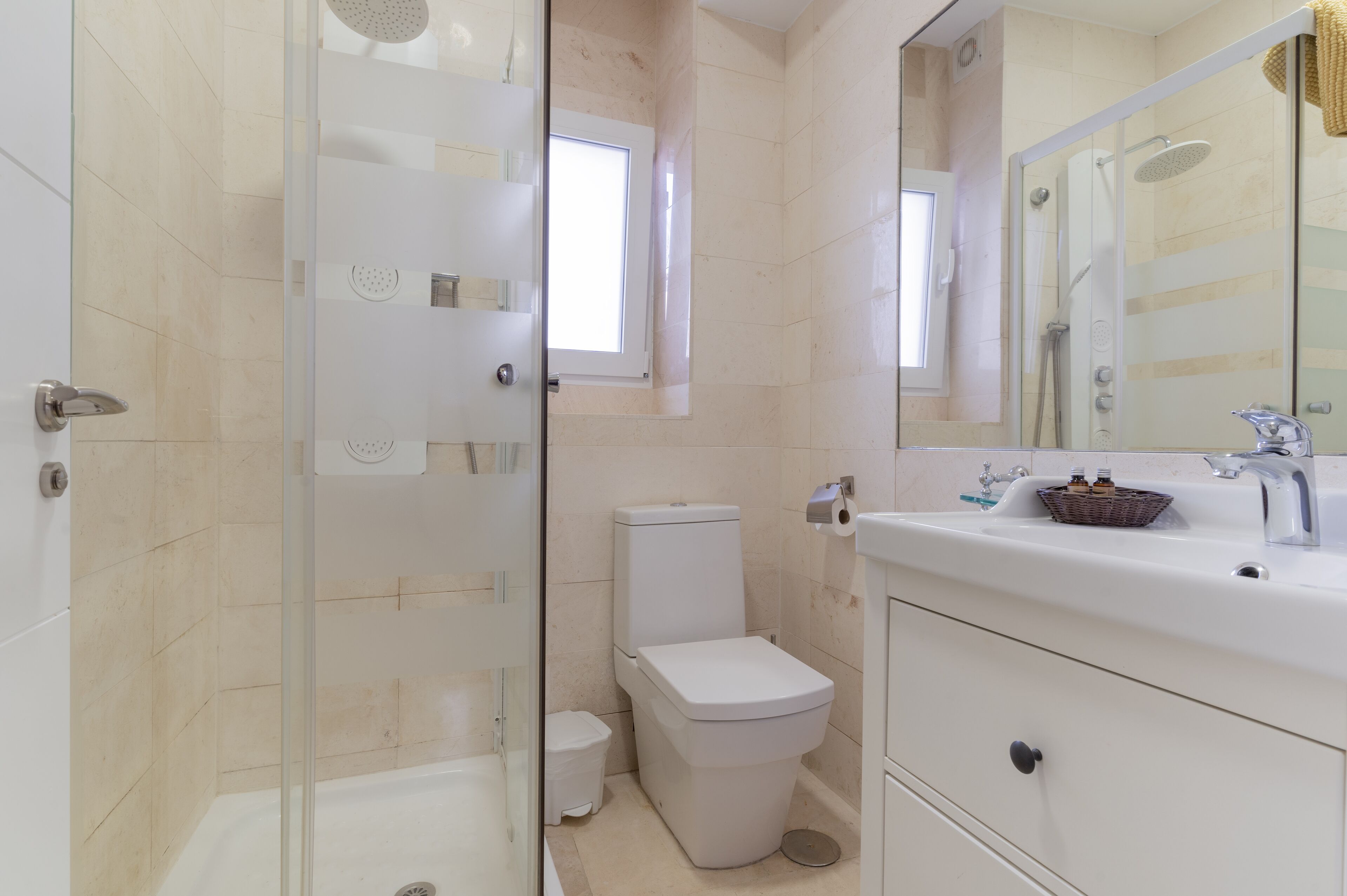 Une salle de bain moderne avec une douche à parois de verre, des toilettes et un lavabo avec un miroir.