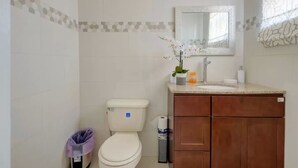 A bathroom with a toilet, sink, mirror, and cabinet. - The Ideal Loft (Nassau)