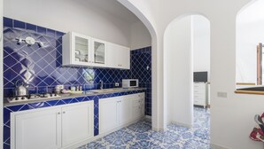 Una cocina con azulejos azules y blancos, armarios blancos y un microondas.