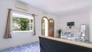 Una habitación con un ventanal grande, una bañera, una mesa de comedor con sillas y un espejo.