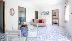 Una habitación con una mesa y sillas de vidrio, un sofá y una cama.