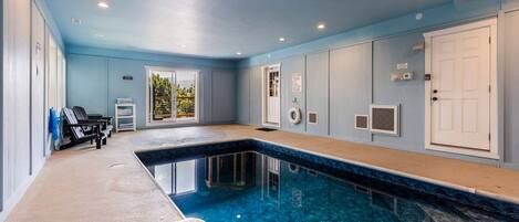 Una piscina con acqua cristallina, un lettino prendisole e un'uscita verso uno spazio esterno.