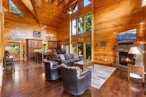 A spacious log cabin interior with a living area, kitchen, and fireplace. - Beaver's Treehouse - Private Pool, Theater, Mountain Views, and Close to Pigeon Forge Parkway! (Pigeon Forge)