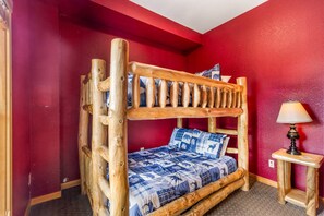 Una cama litera con estructura de madera y ropa de cama azul estampada.