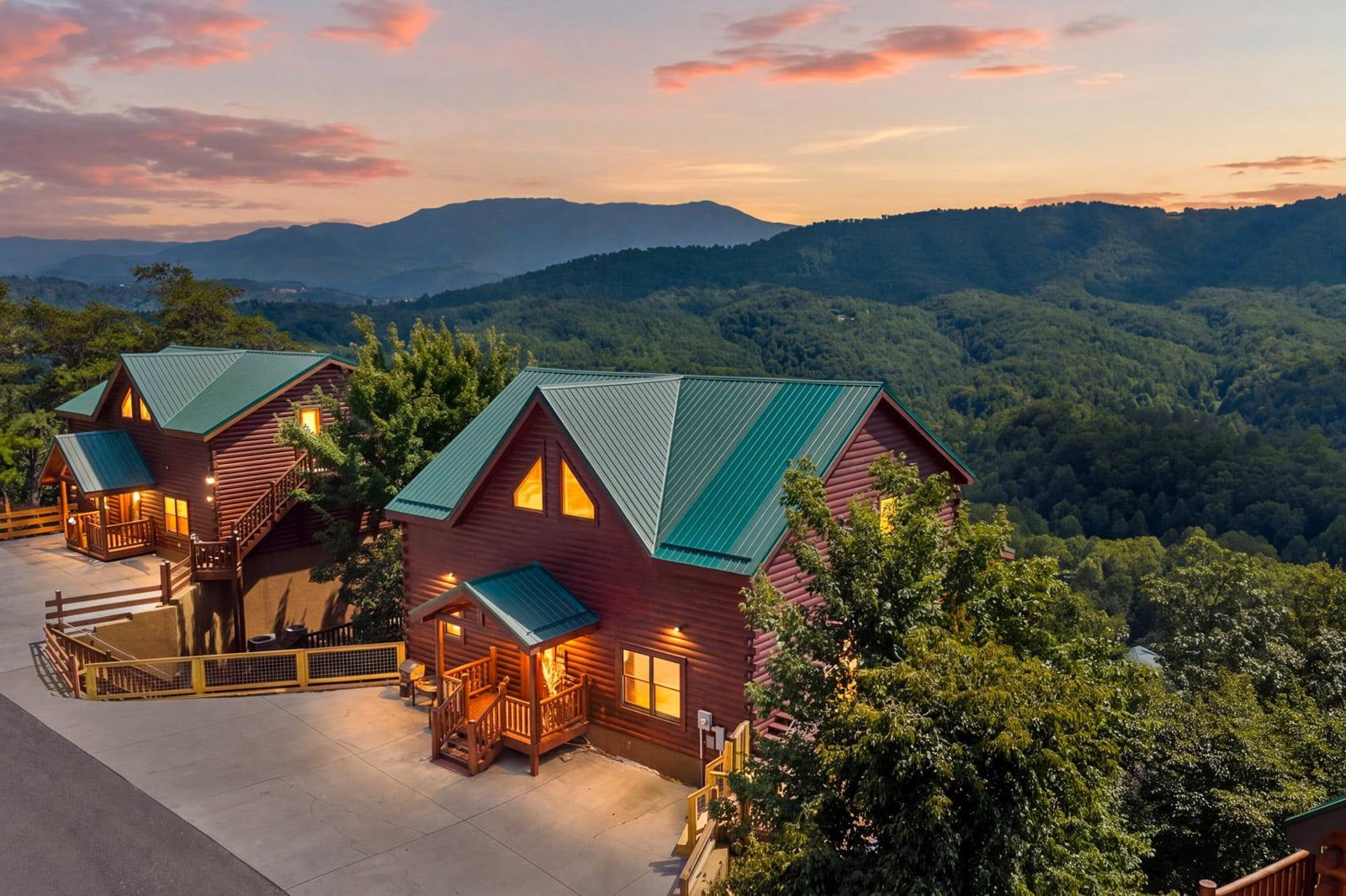 A cabin with a porch, a covered deck, and a view of the surrounding forest and mountains.