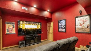 A red-walled room with a large screen, a box office sign, and a poster on the wall. - Beaver's Treehouse - Private Pool and Sauna! (Pigeon Forge)