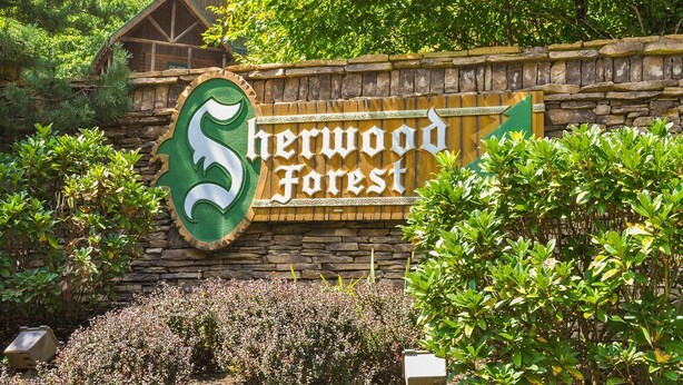 A sign for Sherwood Forest with a large green logo and the name in white letters. - Beaver's Treehouse - Private Pool and Sauna! (Pigeon Forge)