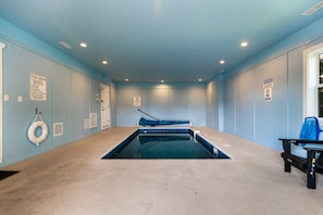 Uma pequena piscina interior com mesa de bilhar azul, boia e placa indicando que mergulhos não são permitidos.