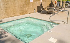 Une piscine rectangulaire avec un escalier en métal et un espace détente comprenant des chaises et des tables.