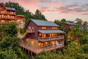A multi-story log cabin with balconies and a deck, surrounded by dense forest. - Beaver's Treehouse - Private Pool, Theater, Mountain Views, and Close to Pigeon Forge Parkway! (Pigeon Forge)