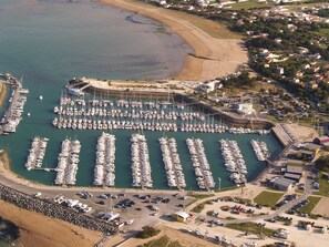 An aerial view of a marina with numerous boats docked, a parking area, and surrounding residential buildings. - Quiet house in a private dead end 150m from the beach. (Saint-Denis-d'Oléron)