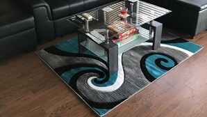 A modern living room with a black leather sectional sofa, a glass coffee table, and a blue and black patterned rug. - Amazing Views and Two Kayaks Ready to Use! (Moneta)