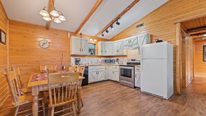 Een knus keuken in chaletstijl, met houten wanden, een eettafel met stoelen en moderne apparatuur.