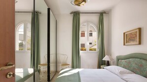 A bedroom with a bed, a chair, a lamp, and a window with curtains.
