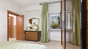 Un dormitorio con cama, cómoda, espejo y ventana con cortinas.