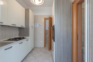 Eine Küche mit weißen Schränken, einem Gasherd und einer gefliesten Spritzschutzwand.
