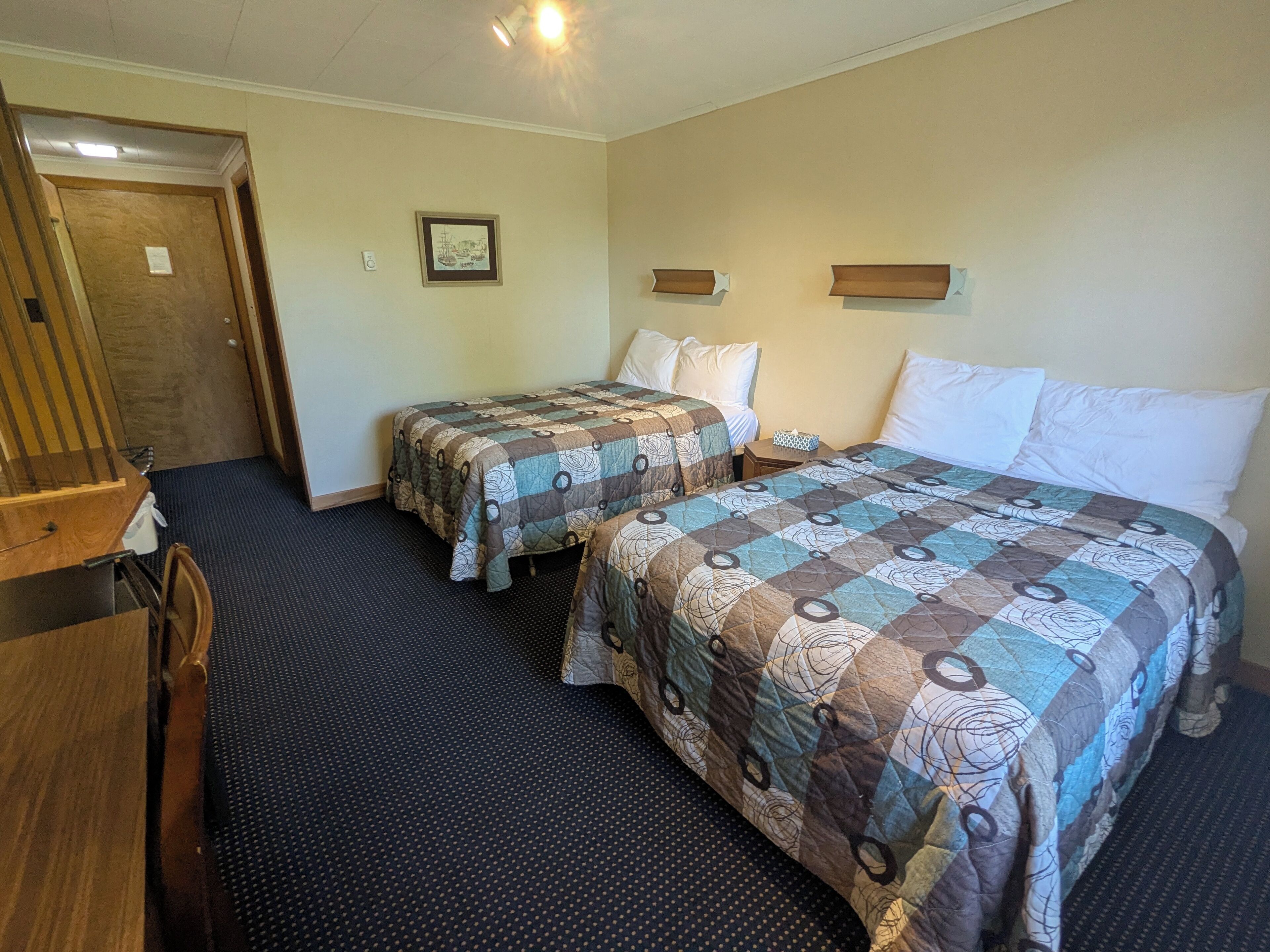 Ett hotellrum med två sängar, ett skrivbord och en dörr.