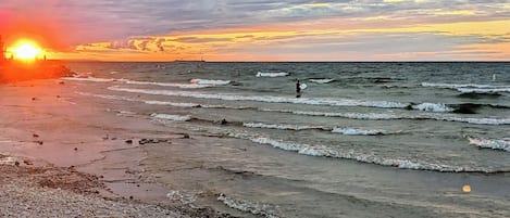 A beach with waves and a sunset.
