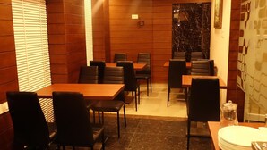 A restaurant with wooden walls, black leather chairs, and tables. - Hotel K square (Chennai)