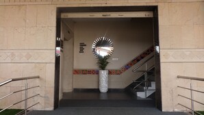 A reception area with a reception desk, a mirror, a potted plant, and a staircase. - Hotel K square (Chennai)