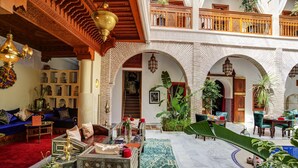 A spacious interior with a high ceiling, ornate wooden beams, and a central courtyard with seating areas and plants. - Riad Janate (Marrakech)