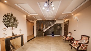 Un hall d’entrée spacieux, doté d’un sol en marbre, d’un escalier et de deux fauteuils.