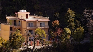 Un immeuble à plusieurs étages doté de balcons, entouré d’arbres.