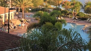 Ein Resort mit Swimmingpool, umgeben von Palmen und Liegestühlen.