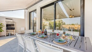 A dining area with a table set for six, outdoor seating, a grill, and a view of the landscape. - Casa Reiet by dracmallorca (Santanyi)