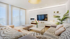 A modern living room with a sofa set, a coffee table, a TV, and a large window. - Casa Reiet by dracmallorca (Santanyi)