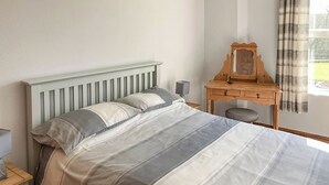 Ein Schlafzimmer mit Bett, Nachttisch, Kommode und Spiegel.