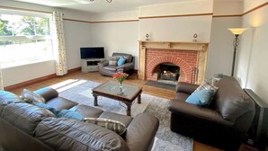 Ein Wohnzimmer mit Kamin, Ledersofas, einem Couchtisch und einem Fernseher.