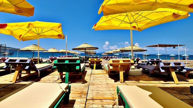 Un espace aménagé sur la plage, avec des chaises longues en bois et des parasols jaunes.