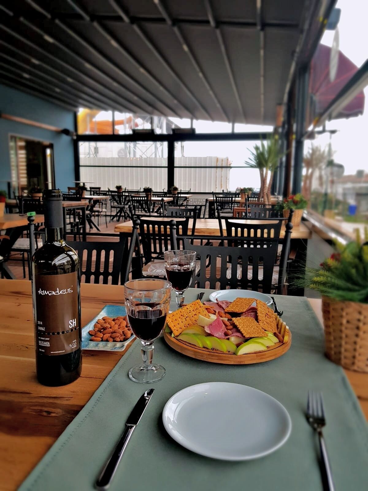 A restaurant setting with a table set for a meal, including a bottle of wine, glasses, and a plate of food.