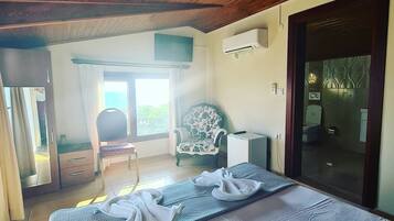 Un dormitorio con una cama, una silla, un armario pequeño y una puerta corredera que da a un baño.