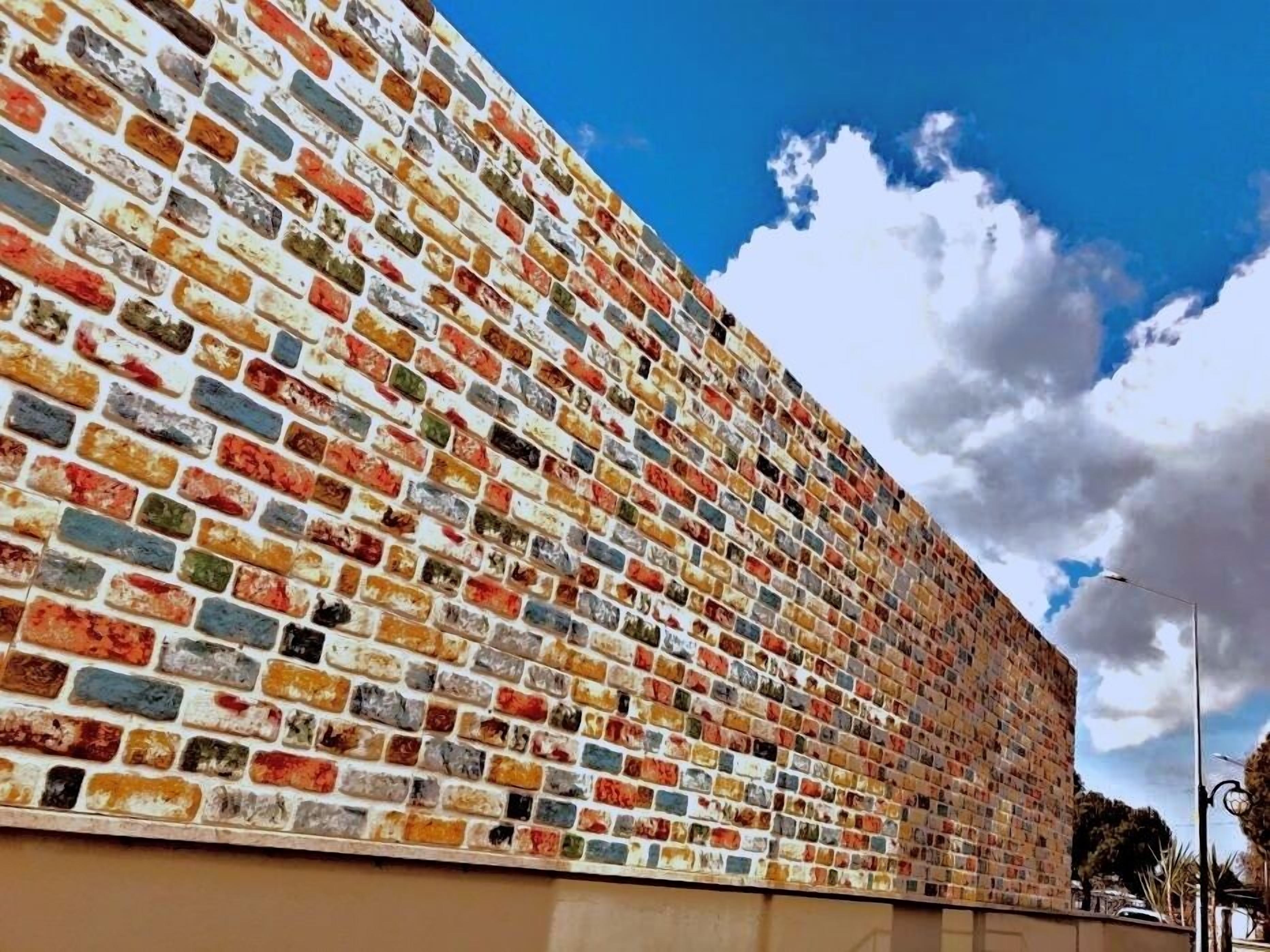 Eine große Wand mit einem Mosaik aus farbenfrohen Fliesen.